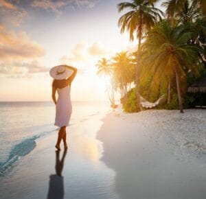 Woman enjoying mindful moment on tropical beach at sunset, stress-free living