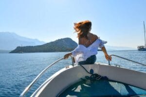 Woman sailing toward island with wind in hair and open arms